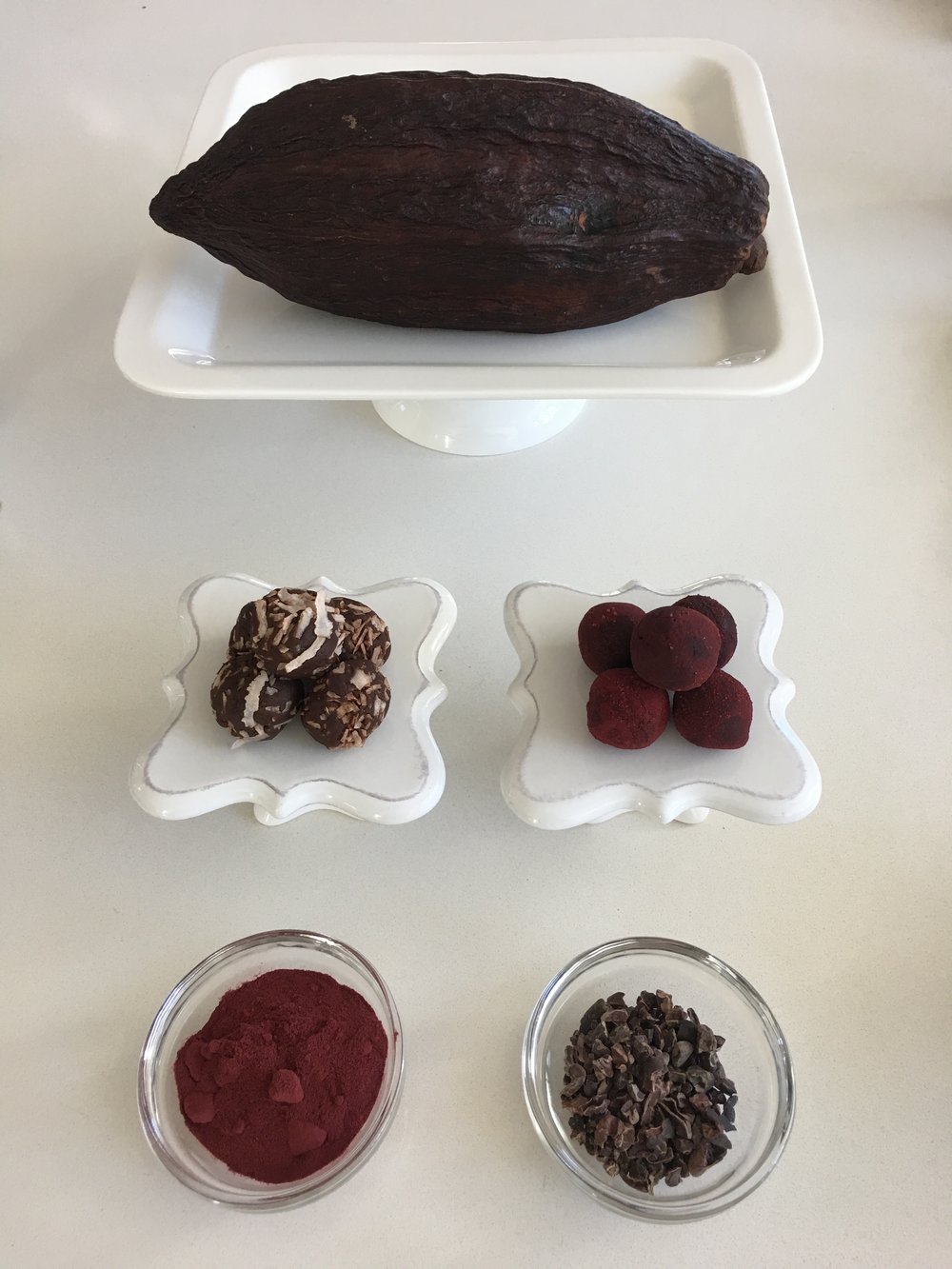 CACAO POD ( top ), Cacao Protein Bites rolled in shredded coconut and beet root powder ( middle ), Beet root powder, Raw cacao nibs ( bottom )